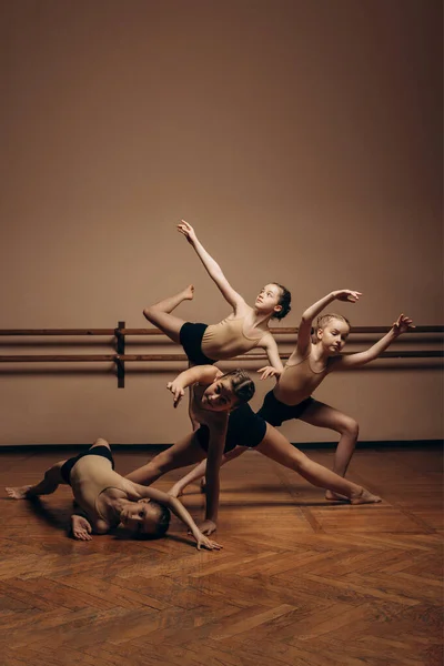 Образ группы современных маленьких балерин в гимнастических костюмах, стоящих в современной танцевальной позе. Копирование пространства — стоковое фото