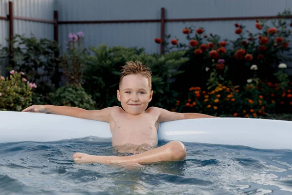 Die süße Fünfjährige entspannt an einem heißen, sonnigen Sommertag in einem aufblasbaren Pool. Konzept der Sommerferien auf dem Land — Stockfoto
