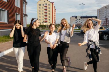Şehirde birlikte yürüyen bir grup mutlu genç kız.