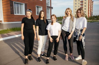 Beş kişilik bir grup neşeli kız arkadaş şehirde dolaşıp kameraya poz verirken eğleniyorlar.