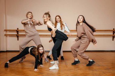 Modern dansçılar bir dans stüdyosunun arka planına poz veriyorlar, modern dansın elementlerini sergiliyorlar, profesyonel dansçılar bir konser için hazırlanıyorlar.