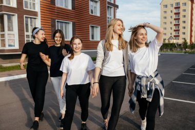 Bir grup neşeli genç kız sokaklarda yürüyor ve gülüyor.