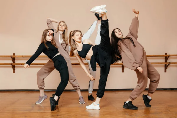 Modern dancers pose against the background of a dance studio, performing elements of modern dance, a professional group of dancers is preparing for a concert