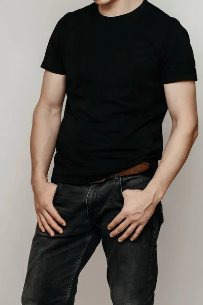 Brutal attractive man poses in a black empty T-shirt made of thin premium cotton, highlighted on a white mock-up — Stock Photo, Image