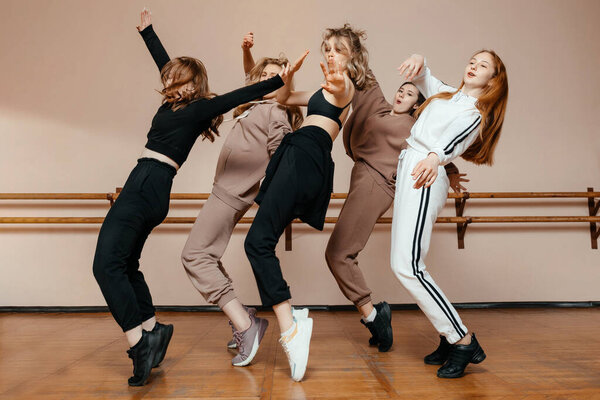 Group of girls in sportswear, performing elements of house dance in a dance studio, dancing with pleasure. The concept of sports youth. 