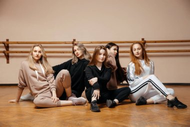 Spor kıyafetleri içinde neşeli kadınlar, duvara yaslanmış, fitness derslerine başlamaya hazır, sağlıklı spor yaşam tarzı kavramı. Y Jenerasyonu kavramı. 