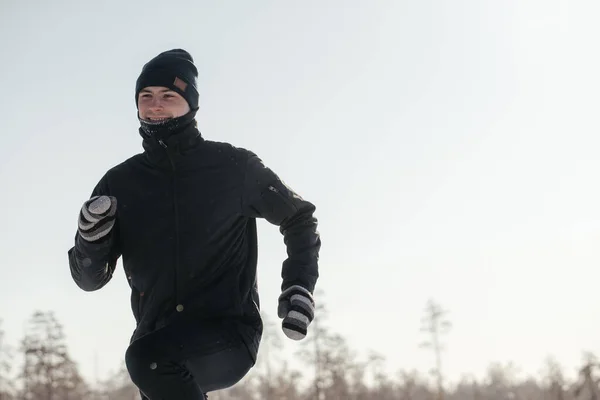 Comprimento total de um atleta de meia-idade feliz correndo na natureza em um dia de inverno nevado. Fitness ao ar livre, treinamento cardio, exercícios ao ar livre Imagens Royalty-Free