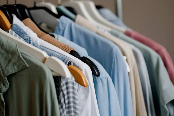 Primer plano de una colorida variedad de camisetas, camisetas y blusas en perchas dentro del armario. boutique de ropa de color pastel. ropa de algodón orgánico. Enfoque selectivo. —  Fotos de Stock