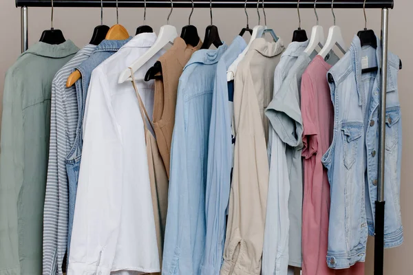 Close-up of a colorful variety of shirts, T-shirts and blouses on hangers inside the closet. boutique of pastel-colored clothing. organic cotton clothing. Selective focus. — Stock Photo, Image