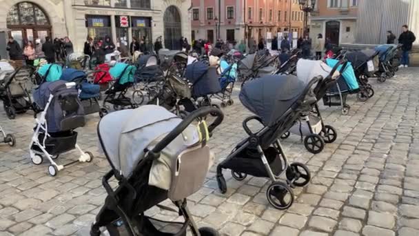 18 marca 2022 - Lwów, Ukraina: Montaż pustych wózków dziecięcych na głównym placu miasta ku pamięci dzieci, które zginęły w wojnie Rosji z Ukrainą. — Wideo stockowe