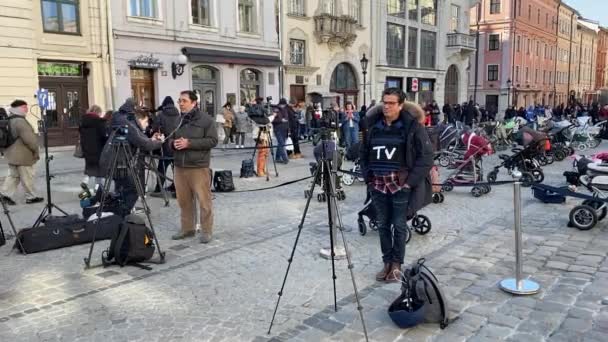 18 de marzo de 2022 - Lviv, Ucrania: Medios de comunicación internacionales hacen un informe desde Lviv sobre una instalación de carruajes vacíos para bebés que representan a niños que murieron debido a la agresión rusa contra Ucrania — Vídeos de Stock