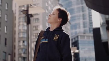 Ukraynalı mülteci çocuk sokakta gökdelenlerin arasında dikiliyor..