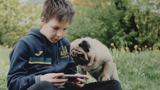 Ukrainian Refugee Boy Hoodie Playing Video Game Smarthphone Sitting Meadow — Stock videók