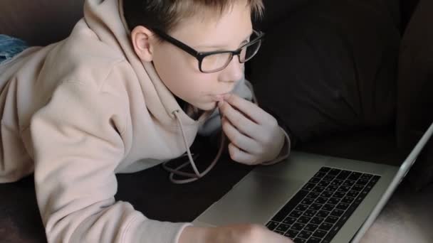 Adolescente Caucasiano Com Capuz Vestindo Óculos Usando Laptop Deitado Sofá — Vídeo de Stock