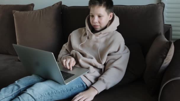 Adolescente Caucasiano Menino Com Capuz Usando Laptop Deitado Sofá — Vídeo de Stock