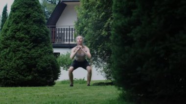 Doing sports in front of the house. Slim caucasian blonde woman in the garden crouching. Healthy lifestyle concept.