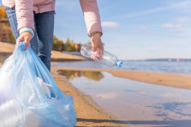 Kadın bir gönüllü doğadaki plastik çöpleri temizliyor..