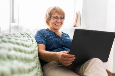 Bir kadın kanepede dizüstü bilgisayarla oturuyor..