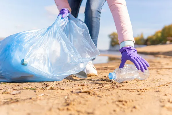 A female volunteer cleans plastic garbage in nature.