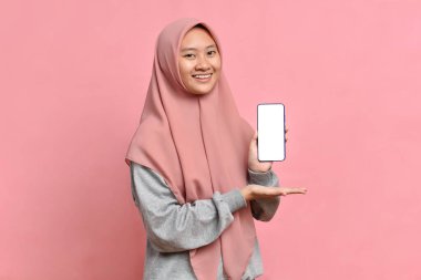 Güzel Asyalı Müslüman kadın gülümseyen portresi telefonda beyaz ekran gösteriyor.