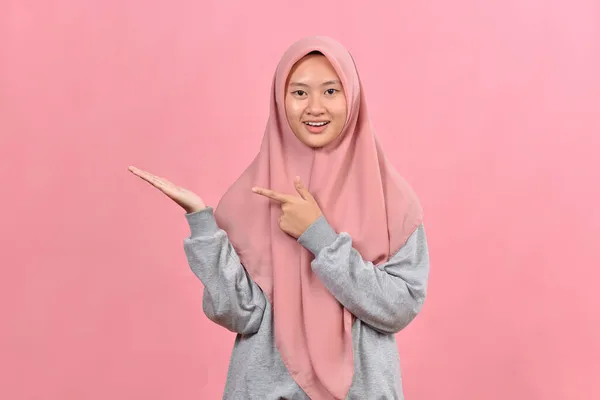 若いですムスリム女性Posingでピンクの背景隔離された励起保持Aコピースペース上の手のひら — ストック写真