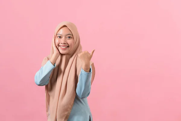 アジアの美しい若いイスラム教徒の女性の肖像画笑顔でコピースペースを指して ピンクの背景に隔離された — ストック写真