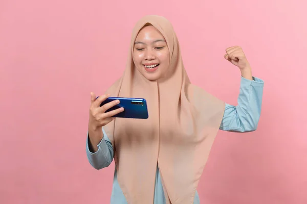 年轻的亚洲少年拿着手机做着获胜的手势 快乐在网上得到特别的礼物 被粉色背景隔离 — 图库照片