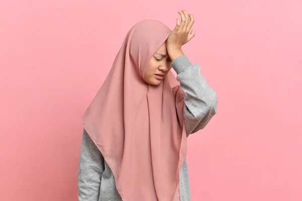 頭痛の種の若いイスラム教徒の女性は彼女の手で彼女の寺院を保持します ピンクの背景に隔離された健康 片頭痛 頭痛の概念 — ストック写真