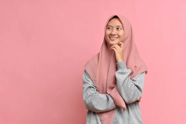 年轻的亚洲穆斯林妇女看着一个复制的空间 或在想一个想法 孤立在粉红色的背景下 — 图库照片