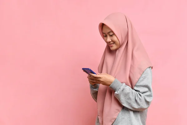Ευτυχισμένος Χαμογελώντας Ασιατική Μουσουλμάνα Γυναίκα Πληκτρολογώντας Στο Κινητό Απομονώνονται Ροζ — Φωτογραφία Αρχείου