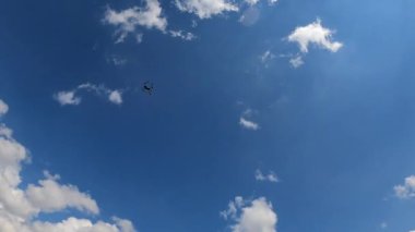 Hava aracı, mavi gökyüzü arka planında bir kuadkopter. İHA gökyüzünde uçuyor. Bulutlu mavi gökyüzü arkaplanında gezinen helikopter aygıtı