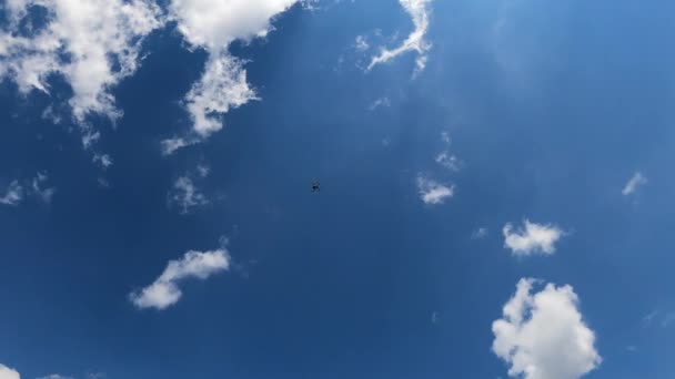 飛行ドローン 青い空の背景にクワッドコプター ドローンが空を飛ぶ 曇り空の背景にホバリングコンピュータデバイス — ストック動画