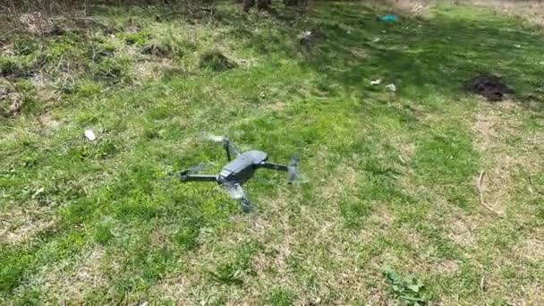 ミニドローンは離陸前に芝生の上で展開しました 小さなドローンが公園の上空を飛んでビデオや写真を撮っています リモコン デリバリーとスパイ — ストック動画