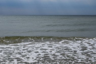 Güzel manzara - turkuaz renkli deniz suyu, kum, gökyüzü. Dalgalar kıyıya vuruyor. Plaj ve Su Sıçratan Dalgalar