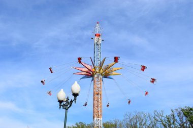 Kharkov, Ukrayna, Mayıs 2021. Yüksek bir kulede dönen bir atlıkarınca. Parkta yüksek zincirli atlıkarınca. İnsanlar bu cazibeye kapılıyorlar. Baharın mavi gökyüzünün arka planında Arabistan atlıkarıncaları.