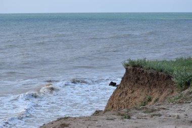 Sahillerin önündeki kayalık kayalık kayalıklar. Mavi Gök ve Su ile Clay Cliffs ve Beach. Deniz kıyısında bir sahil. Göz kamaştırıcı kumsal ziyareti. Büyük kırmızı kayalar ve kayalıklarla mavi gökyüzü