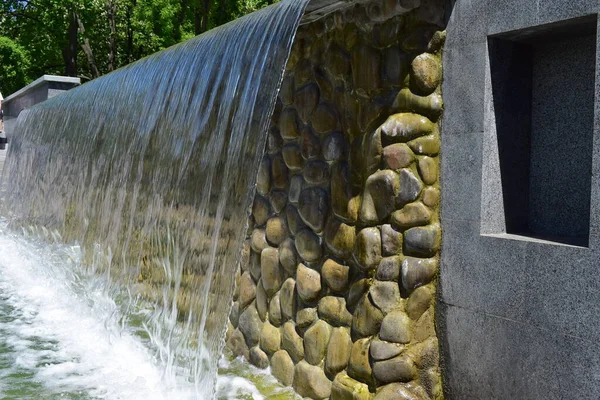 公共公園の庭にある美しい人工滝の風景 都市公園の人工滝 噴水の水は花崗岩のスラブから幅の広いストリップに落ちる — ストック写真