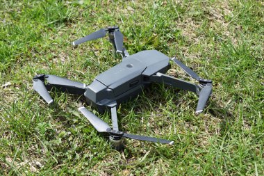 Mini drone havalanmadan önce bir çimlerin üzerine açıldı. Parkta uçan küçük bir dron video ve fotoğraf çekiyor. Uzaktan kumandalı hava dağıtımı ve casus.