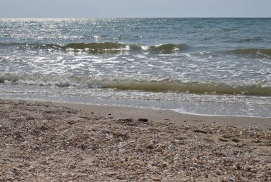 Deniz kumsalı, mavi gökyüzü, kum ve güneş. Yazın dalgalı deniz kıyıları