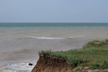 Sahillerin önündeki kayalık kayalık kayalıklar. Mavi Gök ve Su ile Clay Cliffs ve Beach. Deniz kıyısında bir sahil. Göz kamaştırıcı kumsal ziyareti. Büyük kırmızı kayalar ve kayalıklarla mavi gökyüzü