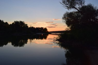 Doğa koruma alanındaki orman gölü üzerinde görkemli renkli gün batımı. Gün batımı ışıklarında güzel bir göl. Manzaralı doğa manzarası. Parlak günbatımı gökyüzü pürüzsüz su yüzeyine yansıyor. Etkileyici gün batımı..