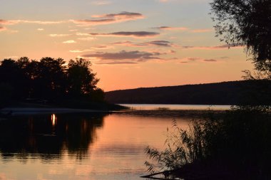 Doğa koruma alanındaki orman gölü üzerinde görkemli renkli gün batımı. Gün batımı ışıklarında güzel bir göl. Manzaralı doğa manzarası. Parlak günbatımı gökyüzü pürüzsüz su yüzeyine yansıyor. Etkileyici gün batımı..