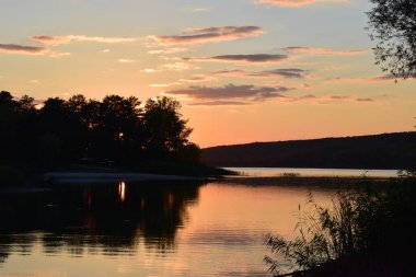 Doğa koruma alanındaki orman gölü üzerinde görkemli renkli gün batımı. Gün batımı ışıklarında güzel bir göl. Manzaralı doğa manzarası. Parlak günbatımı gökyüzü pürüzsüz su yüzeyine yansıyor. Etkileyici gün batımı..