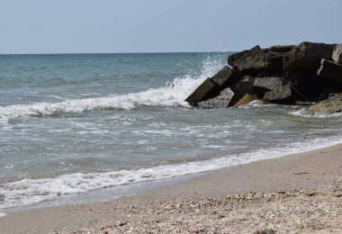 Deniz dalgaları. Açık havada yüksek dalgalar. Denizde güneşli bir gün. Arka plan mavi deniz dalgaları. Islak taşlar ve dalgalar. Tasarım için deniz taşlarının ve deniz kölesinin arka planı.