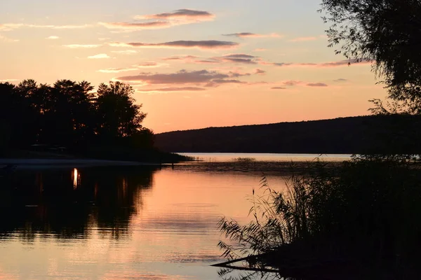 Doğa koruma alanındaki orman gölü üzerinde görkemli renkli gün batımı. Gün batımı ışıklarında güzel bir göl. Manzaralı doğa manzarası. Parlak günbatımı gökyüzü pürüzsüz su yüzeyine yansıyor. Etkileyici gün batımı..