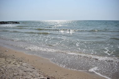 Deniz kumsalı, mavi gökyüzü, kum ve güneş. Yazın dalgalı deniz kıyıları
