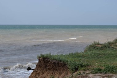 Sahillerin önündeki kayalık kayalık kayalıklar. Mavi Gök ve Su ile Clay Cliffs ve Beach. Deniz kıyısında bir sahil. Göz kamaştırıcı kumsal ziyareti. Büyük kırmızı kayalar ve kayalıklarla mavi gökyüzü