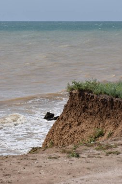 Sahillerin önündeki kayalık kayalık kayalıklar. Mavi Gök ve Su ile Clay Cliffs ve Beach. Deniz kıyısında bir sahil. Göz kamaştırıcı kumsal ziyareti. Büyük kırmızı kayalar ve kayalıklarla mavi gökyüzü