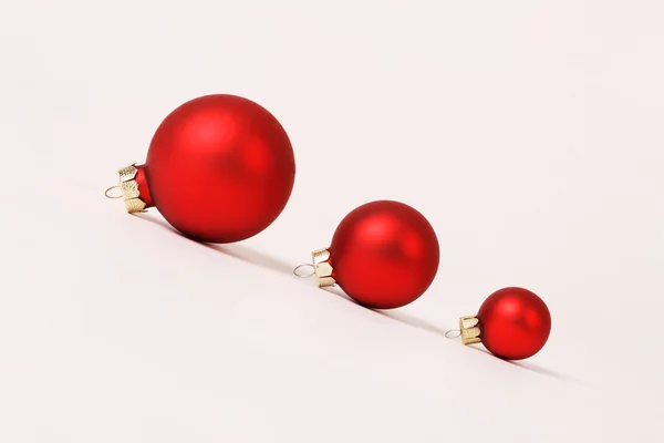 Reihe von drei rot matt verschiedenen Größen Weihnachtskugeln auf rutschigem Hang auf weißem Hintergrund — Stockfoto
