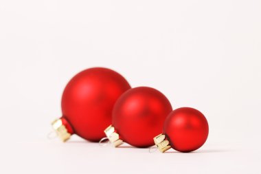 Beyaz arka planda - yatay bir satırda üç mat kırmızı Noel topları